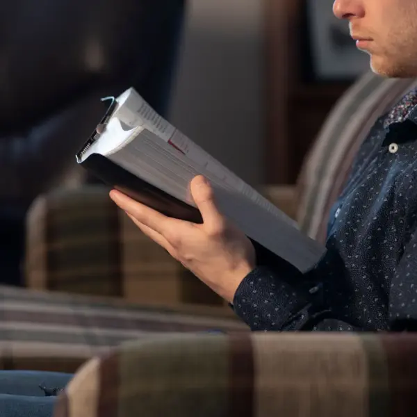 In daily devotional, a young man sits while reading the Bible.
