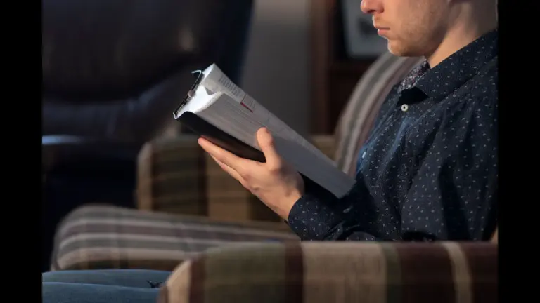In daily devotional, a young man sits while reading the Bible.
