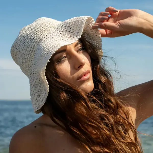 Crochet hats capture the same soft, breezy vibe as a woman wearing a sun hat while she enjoys a sunny day at the seaside in Tallinn, Estonia.