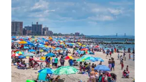 travel chaos unfolds at Coney Island as a vibrant summer scene shows beachgoers, umbrellas, and the shoreline packed with energy.