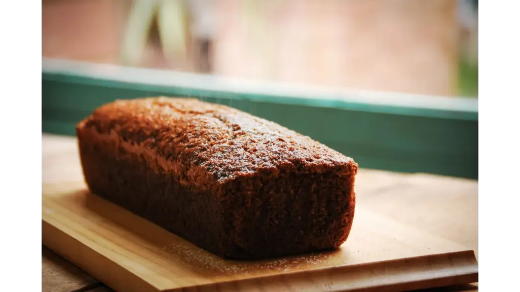 Delicious homemade banana bread loaf placed on a wooden cutting board, perfect for breakfast or a sweet snack.