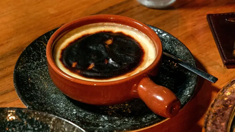Recipe fails show up fast when you’re staring at a close‑up of a rich burnt Basque cheesecake served in a traditional ceramic dish on a wooden table.
