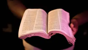 In daily devotional, a worn open Bible is seen held by someone.