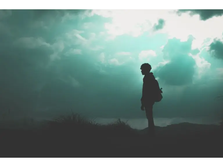  A lone hiker silhouetted against a dramatic cloudy sky, creating an atmospheric scene that reflects the mystery of recurring dreams.