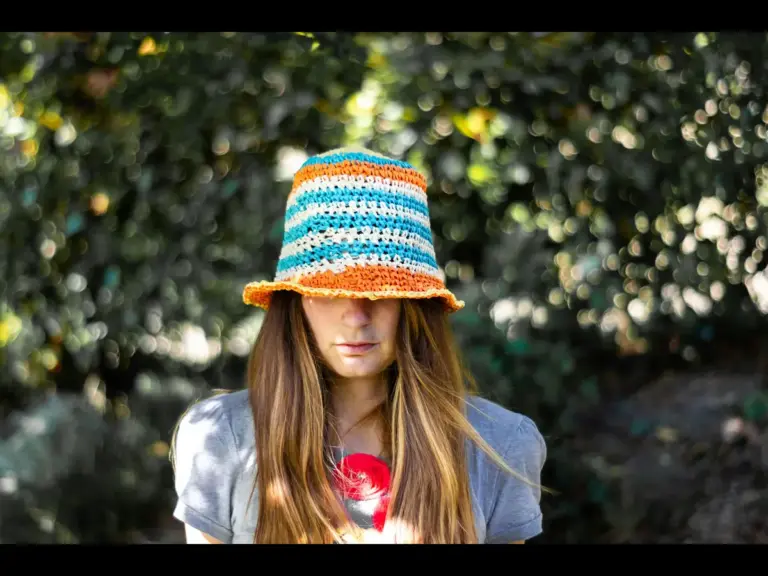 Crochet hats bring the same cozy, colorful charm as a woman wearing a vibrant knitted cap and gray shirt while enjoying the outdoors.
