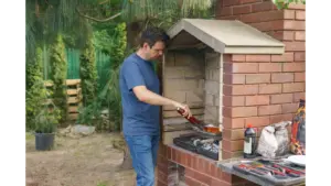 A man grills meat on a brick barbecue in the garden, enjoying outdoor cooking in one of the home’s dedicated BBQ zones.