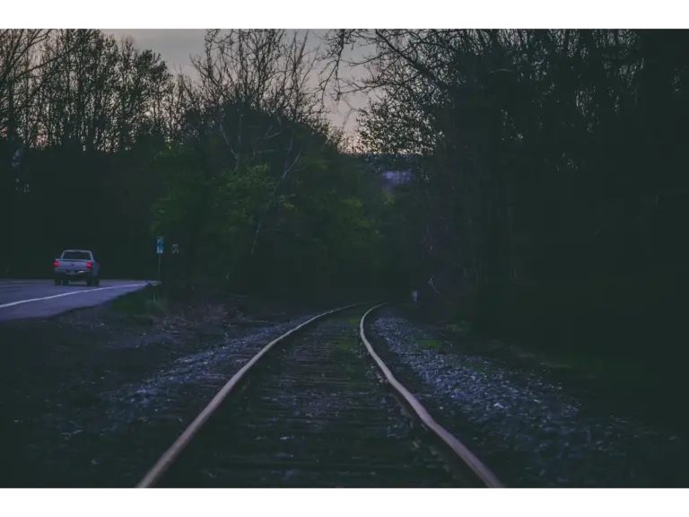 Tranquil scene of train tracks and car on a mystery road in Long Pond, PA at twilight.