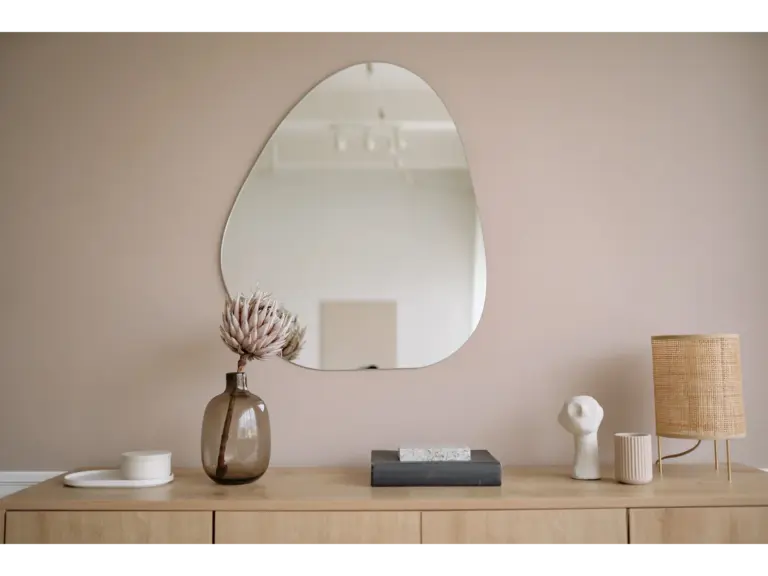 Statement mirrors anchor a stylish minimalist interior featuring a mirror, decorative vase, and lamp, creating a scene that feels curated rather than staged
