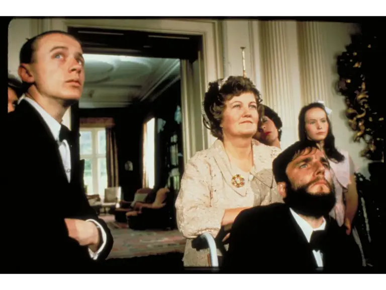 Daniel Day-Lewis and Brenda Fricker in My Left Foot (1989), with a group of people in formal attire looking up in a setting resembling a grand room.