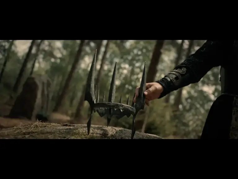A hand reaching for a metallic, spiked object in a forest setting.