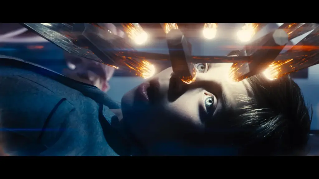 Tyler Maxwell Renaud in Disclosure Day (2026), with wide eyes is lying on a surface with bright lights reflecting above him.