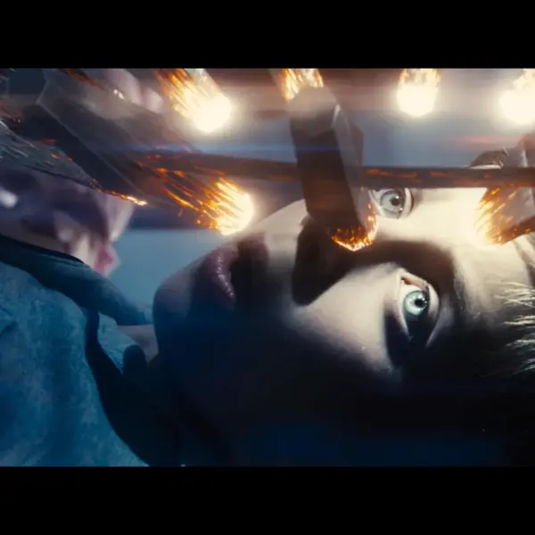 Tyler Maxwell Renaud in Disclosure Day (2026), with wide eyes is lying on a surface with bright lights reflecting above him.
