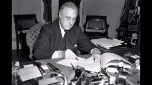 President Franklin D. Roosevelt, half-length portrait, seated at desk, looking down, signing H.R. 1776, the lend-lease bill to give aid to Great Britain, China and Greece.