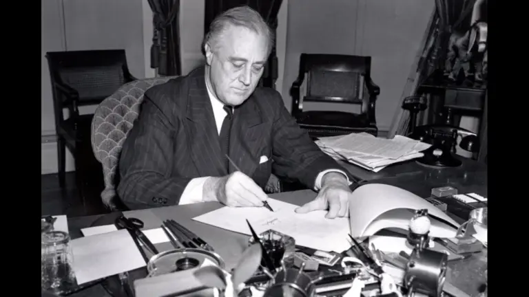 President Franklin D. Roosevelt, half-length portrait, seated at desk, looking down, signing H.R. 1776, the lend-lease bill to give aid to Great Britain, China and Greece.