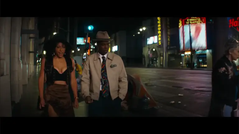 Rosalind Eleazar and Chris Rock walking side by side in Misty Green trailer.