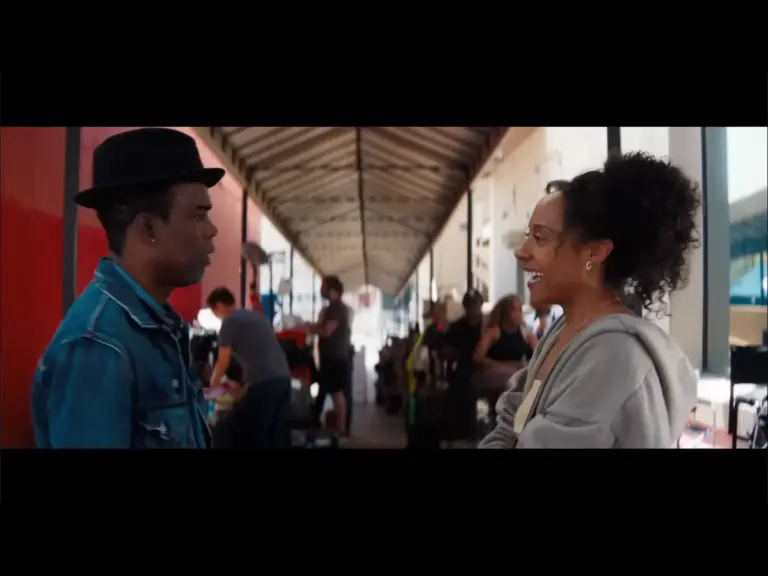 Rosalind Eleazar and Chris Rock looking at each other in a public space in Misty Green trailer.