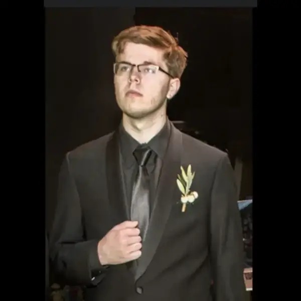 Technoblade in a suit with a gold pendant on it.