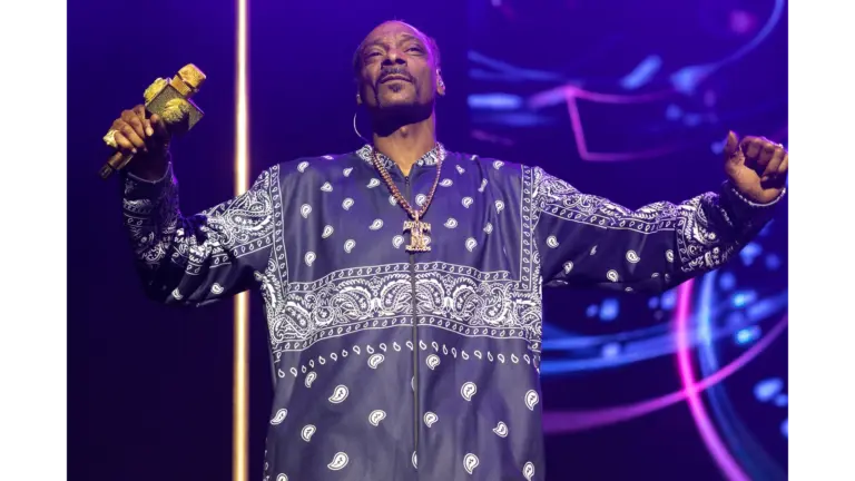 Snoop Biopic — Snoop Dogg performing on stage in a navy bandana-patterned outfit, holding a gold microphone under purple lights.