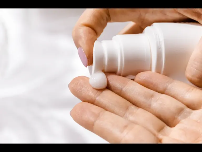 A person dispensing sunscreen onto their hand. 