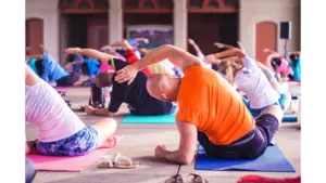 A diverse group of people practice yoga indoors on colorful mats. Stretching to one side, creating a calm and focused atmosphere.