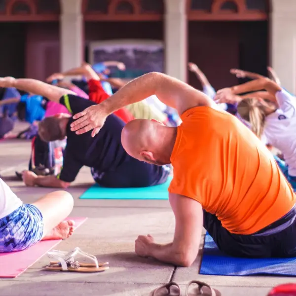 A diverse group of people practice yoga indoors on colorful mats. Stretching to one side, creating a calm and focused atmosphere.