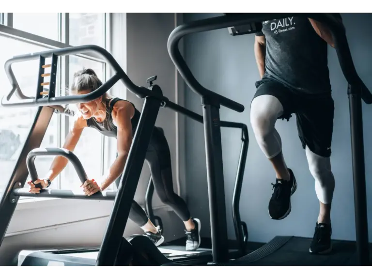 Two people are using different treadmills to exercise in a gym.