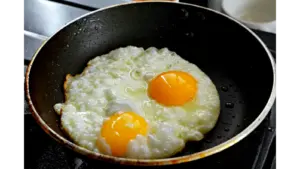 Two eggs sizzling in a frying pan with hot honey caramelizing around the edges, creating sweet‑and‑spicy honey eggs.