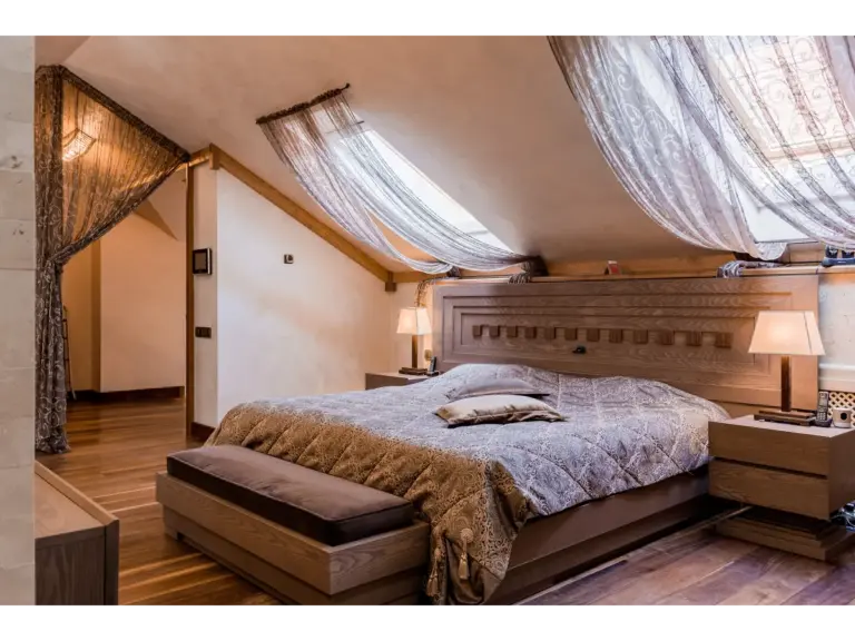 Elegant bedroom interior showcasing luxurious bedding, wooden accents, and draped curtains, styled to create a peaceful home atmosphere.