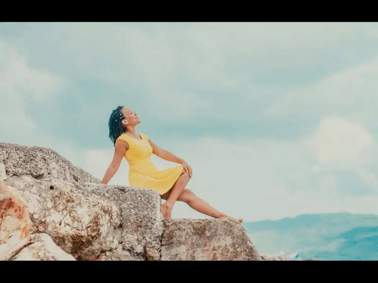 In daily devotional, a woman exudes joy as she sits by the seaside.