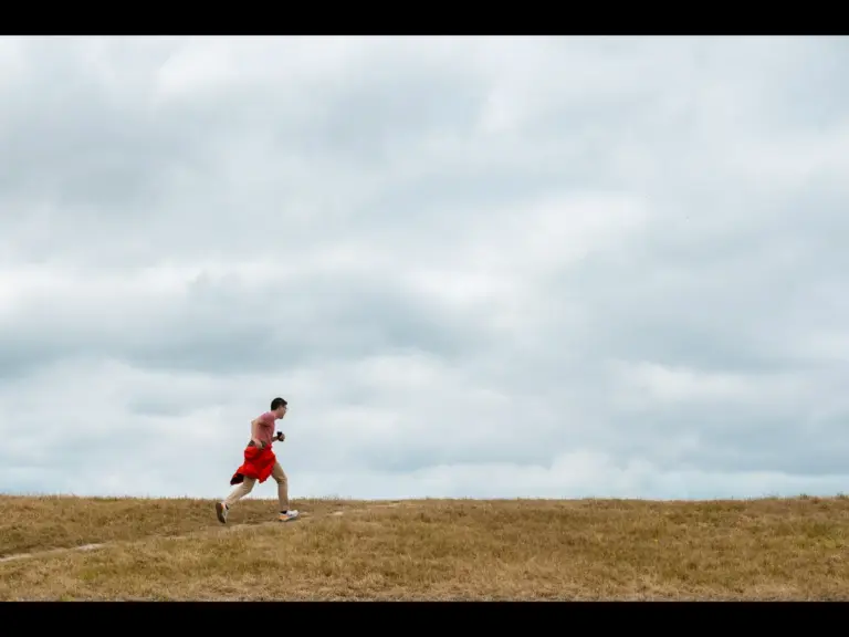 In this daily devotional, a man runs across a vast terrain below a cloudy sky. 