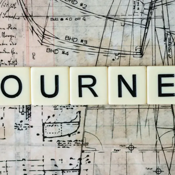 Vintage map background with Scrabble tiles spelling “Journey,” creating a warm, nostalgic travel aesthetic perfect for AI planned adventure themes.