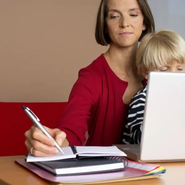 A woman multitasks with a child on her lap while working on a laptop at home, perfectly capturing how Call Preference shifts when real life and remote work collide.