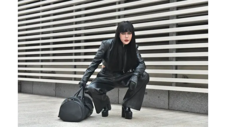 Striking pose of a model in a black leather outfit outdoors, showcasing urban fashion with a bold edge that taps straight into fashion psychology.