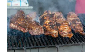 Close-up of delicious grilled smoked ribs smoking on a barbecue grill, perfect for a summer cookout