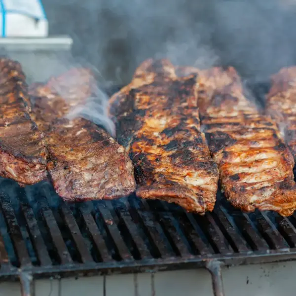 Close-up of delicious grilled smoked ribs smoking on a barbecue grill, perfect for a summer cookout