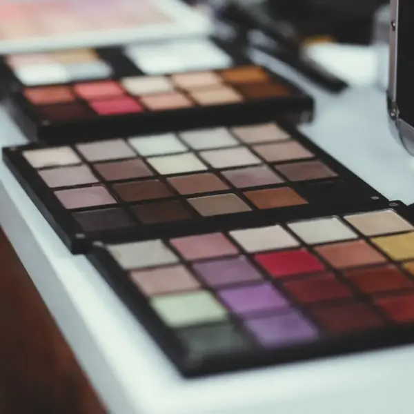 Close‑up of vibrant makeup palettes laid out on a modern white table indoors, each shade arranged to create a flawless tone match moment.