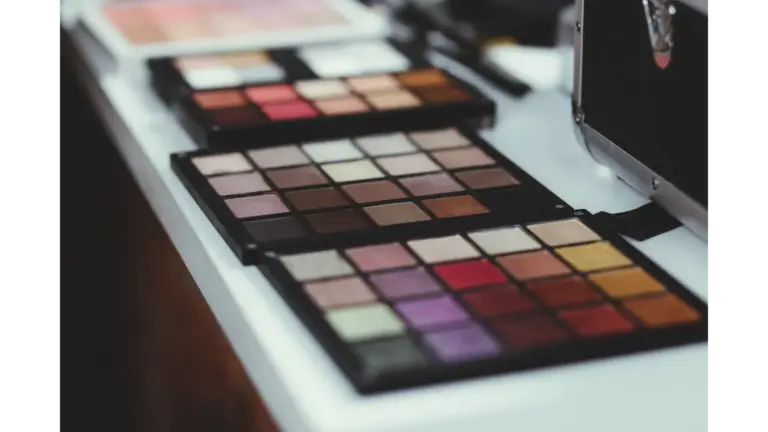 Close‑up of vibrant makeup palettes laid out on a modern white table indoors, each shade arranged to create a flawless tone match moment.