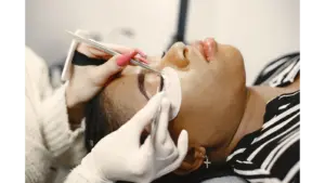 A close‑up view of a woman receiving an eyelash extension treatment in a beauty salon, enhancing her natural lashes with precise, delicate application.