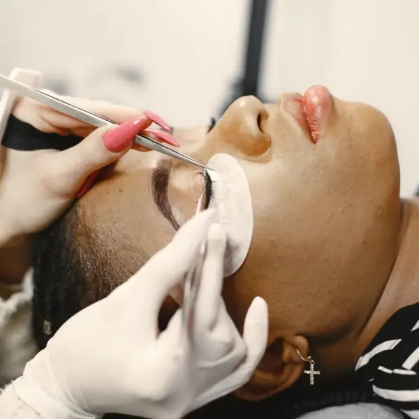 A close‑up view of a woman receiving an eyelash extension treatment in a beauty salon, enhancing her natural lashes with precise, delicate application.