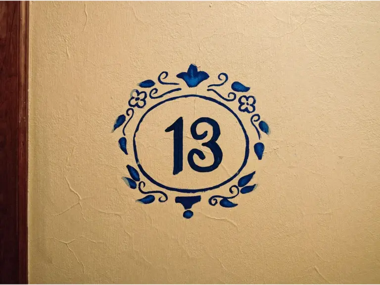 Artistic number 13 painted on a textured wall, symbolizing the everyday superstitions tied to this famously unlucky number.