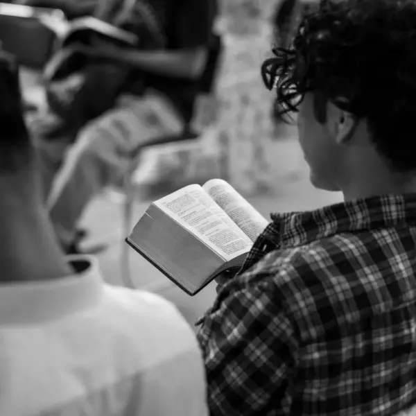 In this daily devotional, a young man is studying the Word of God in a claccroom with others.