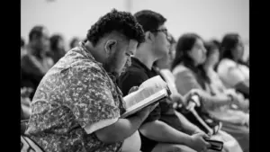 In Wednesday's daily devotional, a man reads the Bible in a classroom with other students.
