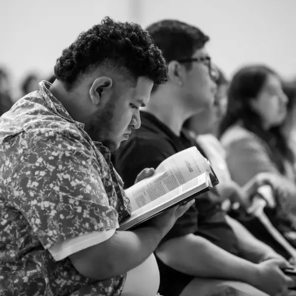 In Wednesday's daily devotional, a man reads the Bible in a classroom with other students.