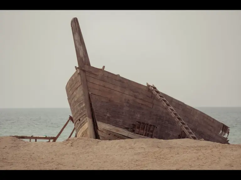 In daily devotional, a large,ancient-style boat is shown near the ocean. 