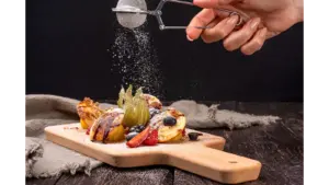 Close-up of pancakes topped with berries and dusted with sugar on a wooden board, capturing the sweet, cozy spirit of the butter craze.