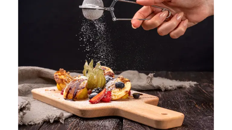 Close-up of pancakes topped with berries and dusted with sugar on a wooden board, capturing the sweet, cozy spirit of the butter craze.