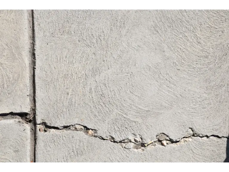 Close‑up view of a cracked concrete surface with distinct textures, subtly echoing the everyday superstitions tied to stepping on cracks.