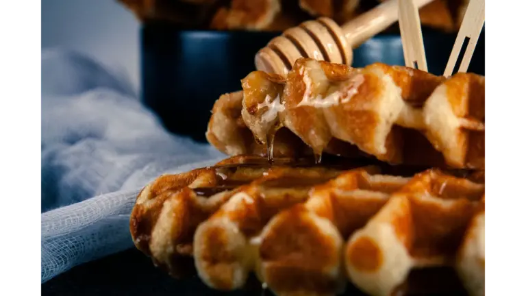 Close-up of warm cinnamon waffles drizzled with honey, served on a black plate for a delicious breakfast treat