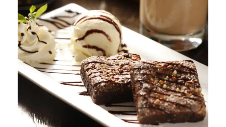 Decadent hot fudge brownies with vanilla ice cream and whipped cream on a white plate