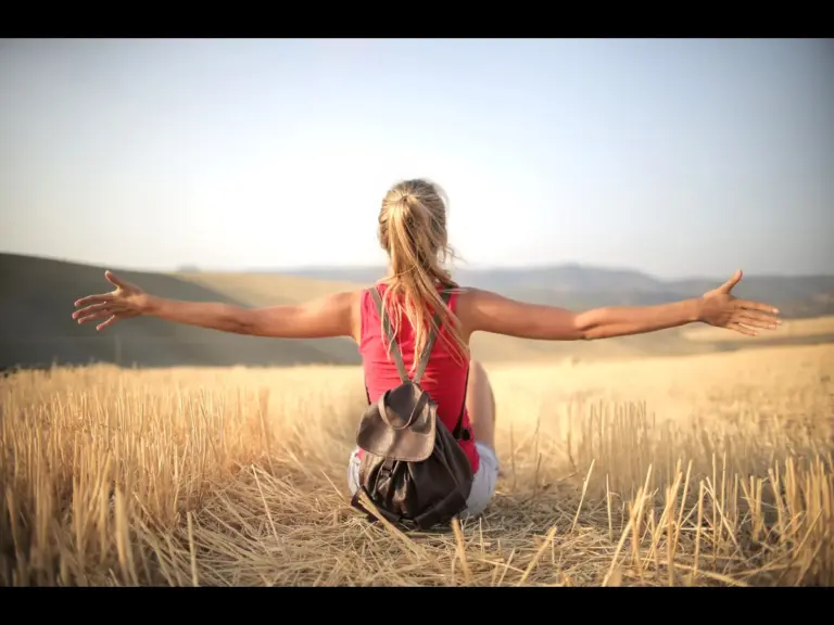 In this daily devotional, a woman sits in the middle of a sunny field, soaking in the goodness of God.